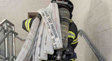 Firefighter carrying Ace Fire Defense Fire Hose up the staircase