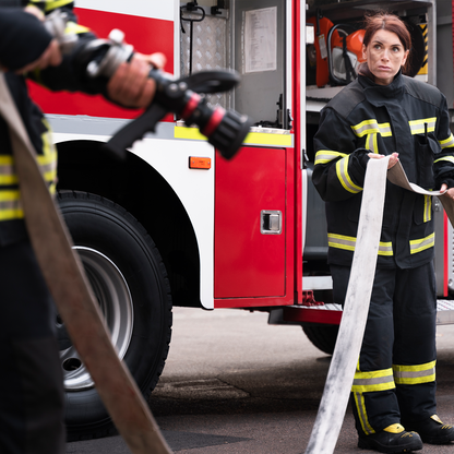 Firefighter holding a hose in front of a fire truck