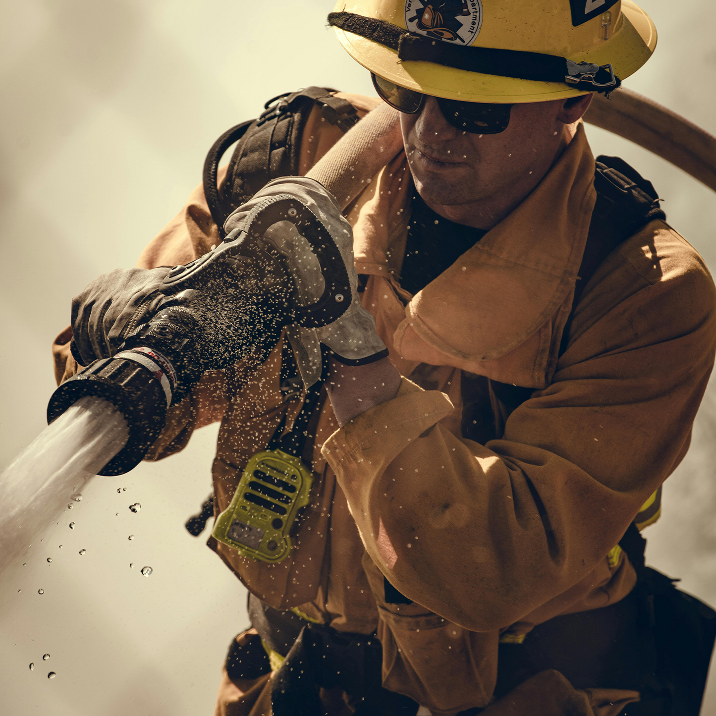 Firefighter in action, holding a hose with a neutral background