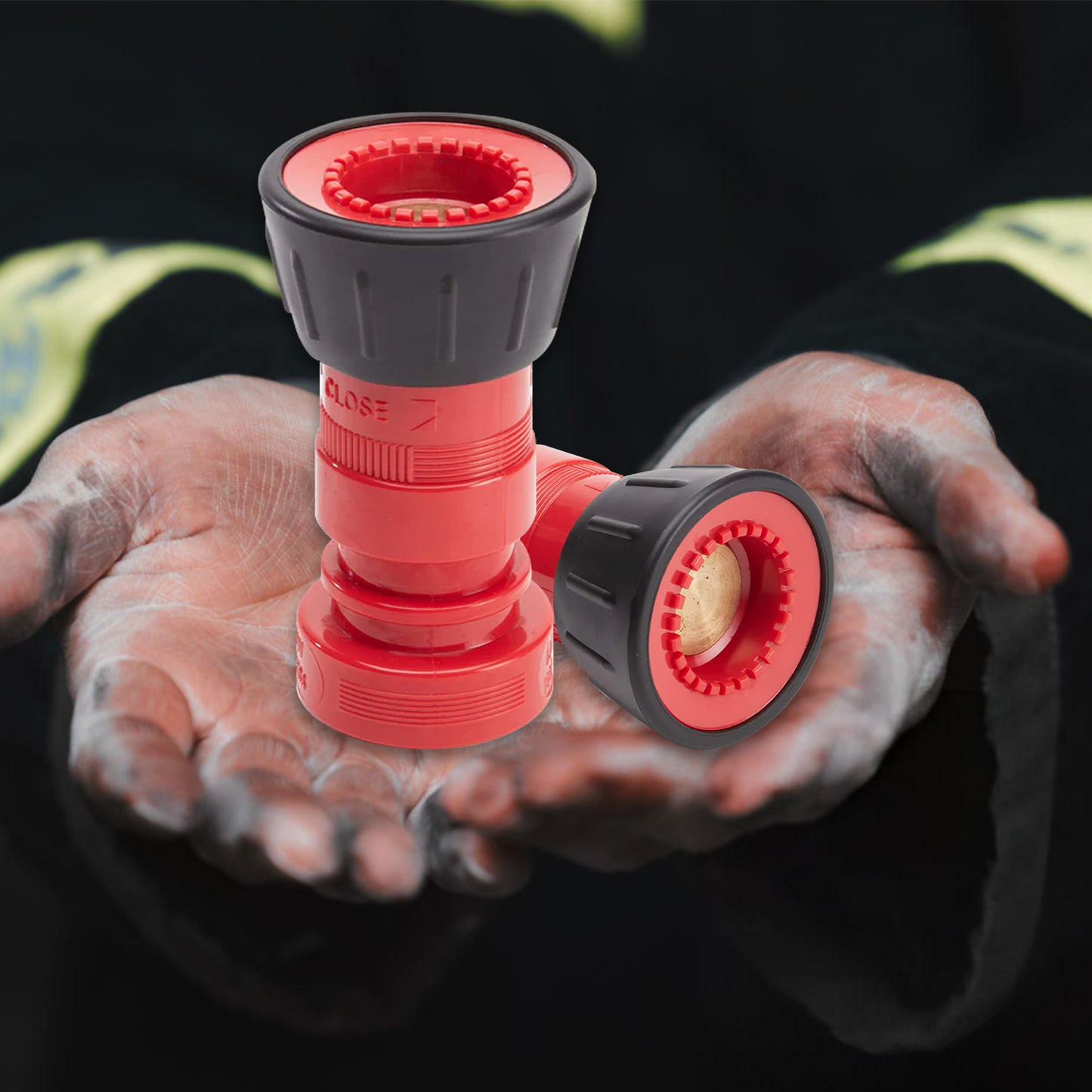 Red and black hose nozzle held in hands with a dark background