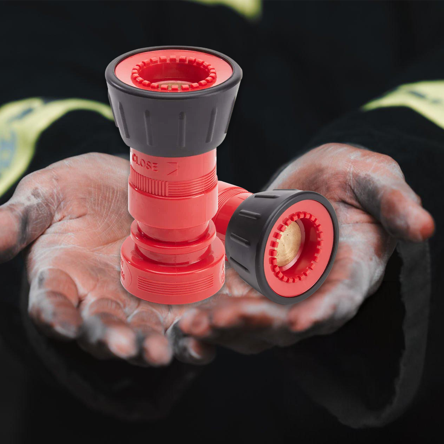 Red and black hose nozzle held in hands with a dark background